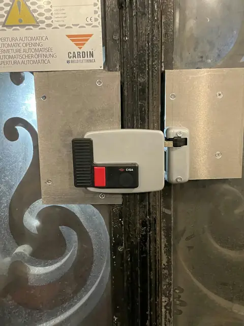 Serrure électrique en applique posée sur une porte en fer forgé